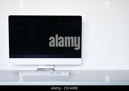 Blank computer screen with mouse and keyboard on the office desk, white background Stock Photo