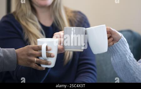 Three ladies drinking coffee together at home. Stock Photo