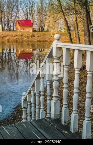 railing with balusters on the background of a wooden cottage with a red ...