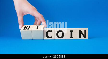 Bitcoin symbol. Turned wooden cubes with words Bitcoin and Coin. Businessman hand. Beautiful blue background. Business and Bitcoin concept. Copy space Stock Photo