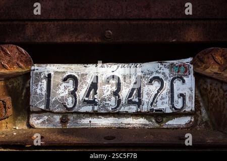 A weathered and rusted license plate, displaying the number 1343426, is affixed to a similarly aged and corroded metal surface. Stock Photo