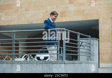 Businessman leaning on railing and using smartphone Stock Photo