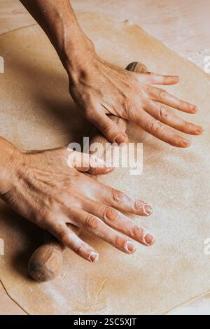 Homemade pasta preparation in Tuscany. The image shows the hands of a woman rolling, shaping and cutting fresh pasta dough, pappardelle & gnocchi. Stock Photo
