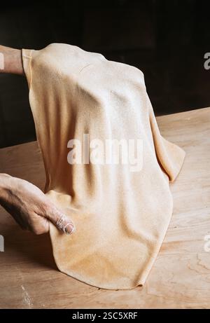 Homemade pasta preparation in Tuscany. The image shows the hands of a woman rolling, shaping and cutting fresh pasta dough, pappardelle & gnocchi. Stock Photo