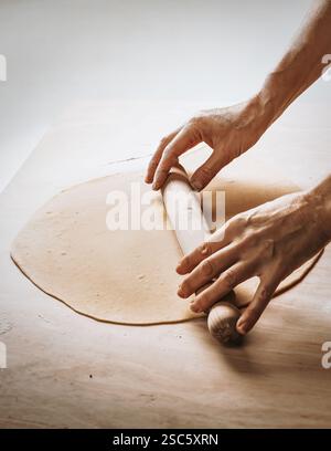 Homemade pasta preparation in Tuscany. The image shows the hands of a woman rolling, shaping and cutting fresh pasta dough, pappardelle & gnocchi. Stock Photo