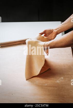 Homemade pasta preparation in Tuscany. The image shows the hands of a woman rolling, shaping and cutting fresh pasta dough, pappardelle & gnocchi. Stock Photo