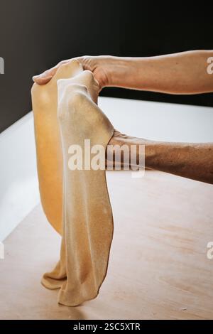 Homemade pasta preparation in Tuscany. The image shows the hands of a woman rolling, shaping and cutting fresh pasta dough, pappardelle & gnocchi. Stock Photo