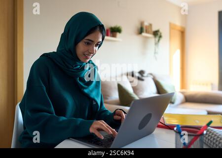 Young muslim woman working from home on laptop Stock Photo