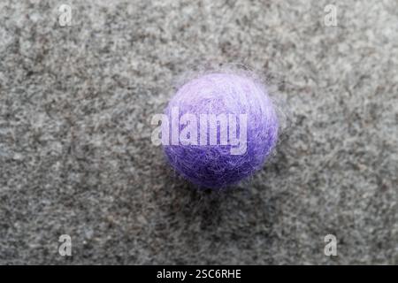 round purple felt ball with gray felt background Stock Photo