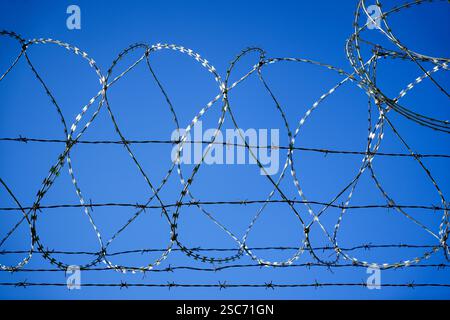 Barbed wire fence against blue sky Stock Photo