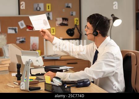 Male FBI agent in headset with fingerprint at office Stock Photo