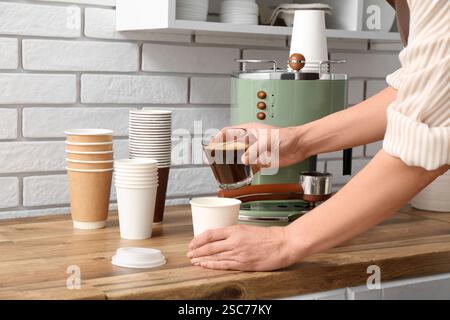 Young female barista making coffee with coffee machine in coffee shop Stock Photo