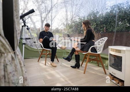 Two young entrepreneurs are having a business meeting using a laptop in a modern bubble tent office, enjoying the natural light and outdoor view, with Stock Photo
