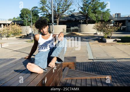 Young Latino man posing on a wooden platform in a square Stock Photo