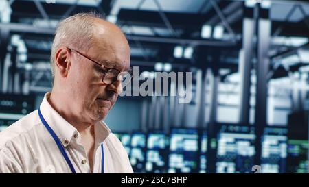 Competent professional in data center, solving tasks on tablet while running scripts on laptop terminal. Skillful developer amidst servers, accessing databases and manipulating lines of code, close up Stock Photo