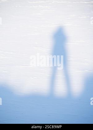 Shadow of a senior woman standing on a snowy embankment in Sawhill Ponds Park near Boulder, Colorado. Stock Photo