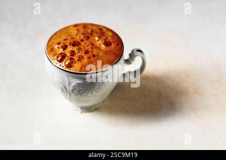 Cup of coffee with nice foamy and bubble surface, closeup on dirty white background. Stock Photo
