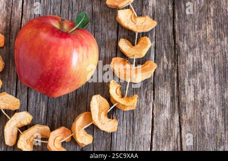 Dried sliced apple fruit with ripe fresh red apples on wooden rustic background, homemade dry fruit concept Stock Photo