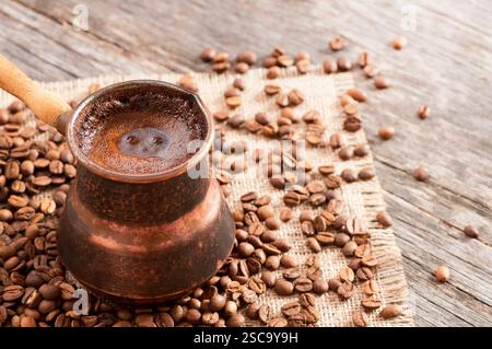 traditional turkish coffee in copper coffee pot with coffee beans on burlap sack, hot drink concept Stock Photo