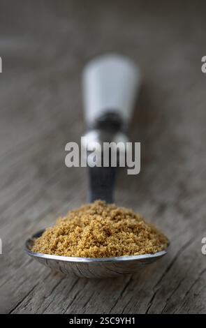 Perspective view of Powdered brown sugar or Brown granulated sugar in Silver spoon isolated on Old rustic wooden table. use it as your Copy space, Des Stock Photo