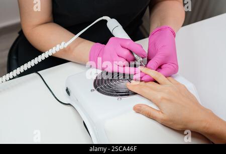 Close up photo of manicure specialist shaping nails with precision using electric nail polisher tool. Beauty salon self-care routine healthy nail trea Stock Photo