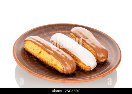 Three eclairs with cream filling on a ceramic saucer, close-up, isolated on a white background. Stock Photo