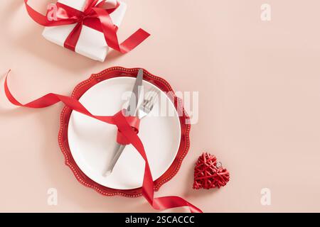 Valentines day table place setting with romantic gift on pink background. View from above. Festive dinner. Copy space. Stock Photo