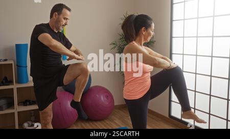 Middle-aged hispanic couple practicing exercise indoors, featuring a man and woman in a gym setting, displaying love for fitness and healthy living to Stock Photo