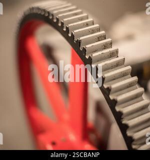 Gear Wheel Macro: Close-up view of a red gear wheel with white teeth, emphasizing precision in industrial design and mechanical engineering. Stock Photo