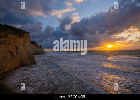 Sunset over dramatic coastal cliffs and a restless sea. Stock Photo
