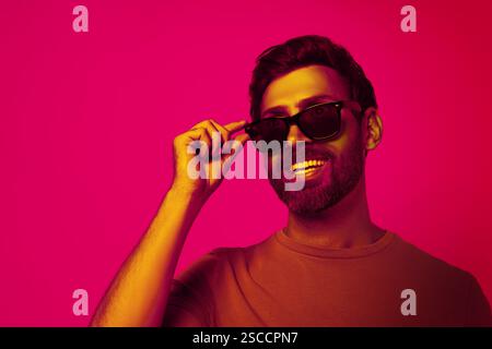 Bearded man with stylish sunglasses smiling in neon light, space for text. Banner design Stock Photo