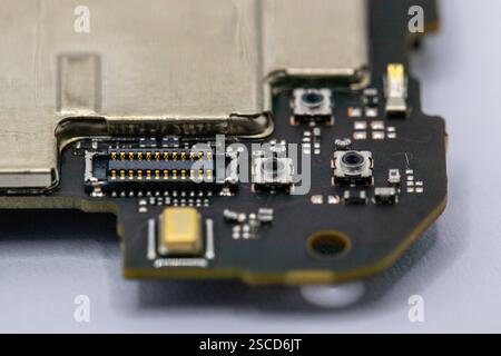 Close-up view of a circuit board fragment, showcasing gold connectors, surface-mount components, and small switches. The board is predominantly dark-c Stock Photo