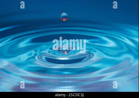 Water drop falling into water making a perfect concentric circles Stock Photo