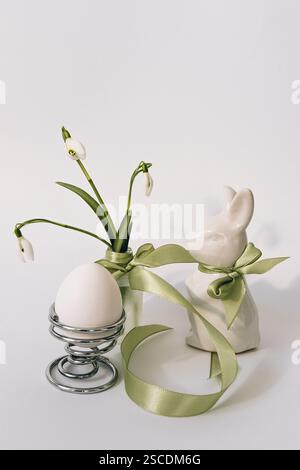 Spring, Easter composition with bunny and spring flowers. In a small vase there are snowdrops and an Easter bunny on a white background. Stock Photo