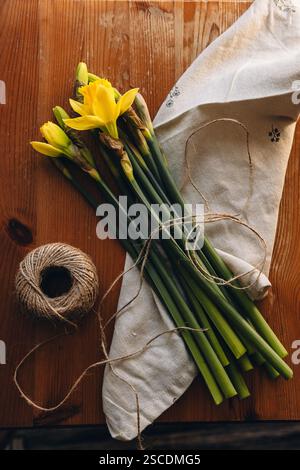 Daffodils on a wooden table on a sunny day indoors. Yellow narcissus or daffodil flowers. Spring flowers background. Spring card with place for text. Stock Photo