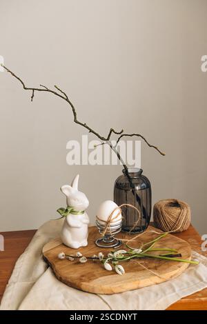 Spring composition with a white bunny, Easter egg and snowdrop flowers on a light background. Easter concept. Place for an inscription. Stock Photo