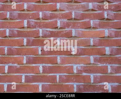 A uniquely patterned brick wall with tilted bricks, creating a dynamic wave effect. Stock Photo