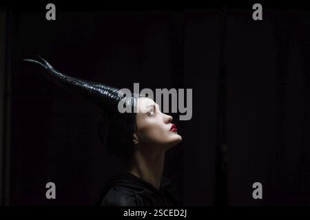 A figure with a horned headpiece looking upward in dramatic lighting Stock Photo