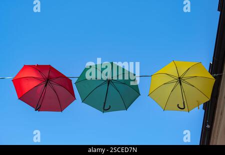 Three colorful umbrellas hanging upside down against a clear blue sky. Stock Photo