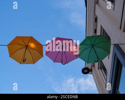 Three colorful umbrellas hanging upside down against a blue sky. Stock Photo