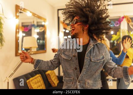Happy latin man dancing moving curly hair at home night party Stock Photo