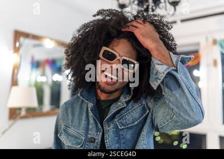Close-up portrait of a cool latin man with curly afro hair and sunglasses smiling during home party Stock Photo
