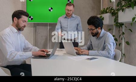 Male leader speaker coach talking to team multiracial men listen to CEO businessman teaching employees showing business presentation at group Stock Photo