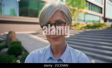 Smiling thoughtful dreaming adult mature Caucasian woman senior old middle-aged businesswoman outside successful business lady elderly female joyful Stock Photo