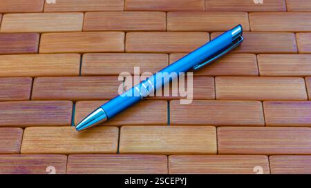 Blue ball point pen retracted on wood bacckground Stock Photo