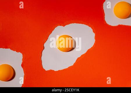 Eggs made of orange torn paper on a white background with ping pong balls. Abstract creative pattern Stock Photo