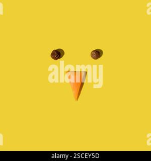 Easter chick face made of pepper and carrot on yellow background. Easter minimal concept. Flat lay. Stock Photo