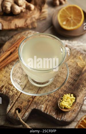 Herbal tea made of fresh ginger root with cinnamon sticks and lemon on a wooden table Stock Photo