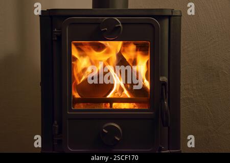 Fire in wood burning fireplace provides a cozy warm atmosphere. Front view of an old cast iron fireplace with burning wood fire and blazing flames. Stock Photo