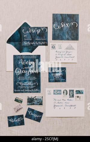 A beautifully arranged wedding invitation set, including RSVP cards and envelopes, showcasing a navy blue theme with elegant calligraphy. Decorative d Stock Photo